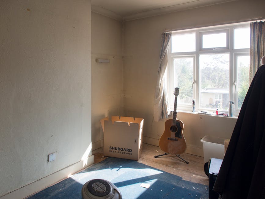 A room with a light-colored wall featuring a standard electrical socket. In the foreground, there is a white sofa draped with a crumpled white sheet or cover, occupying most of the lower left side. To